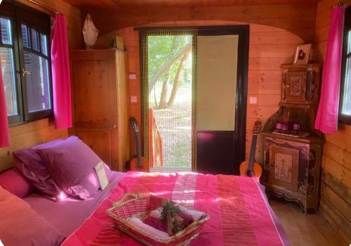 a bedroom with a bed with pink sheets and a window at Roulotte de luxe avec piscine partagée à Ramatuelle in Ramatuelle