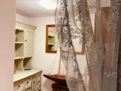a room with a curtain and a boat on the wall at Sunnybrae Cottage in Tintagel