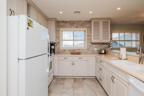 a kitchen with white cabinets and a refrigerator at Fish Tales by Oak Island Accommodations in Oak Island