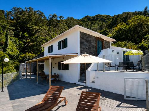 a house with a patio with chairs and an umbrella at VViP Vila Madeira in São Vicente