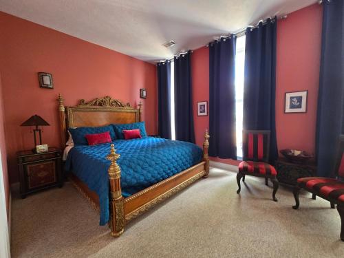 a bedroom with a bed with blue sheets and red walls at Natchez Manor Bed & Breakfast in Natchez