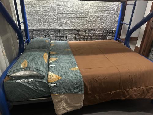 a bed with a brown bedspread and two pillows at Departamento con parqueadero céntrico in Baños