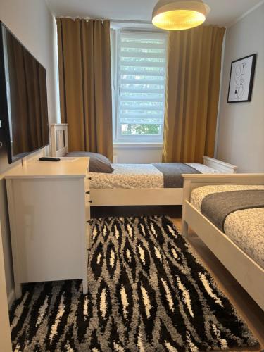 a bedroom with two beds and a window and a rug at Apartament Rodzinny - Classic Olszowa - in Włocławek