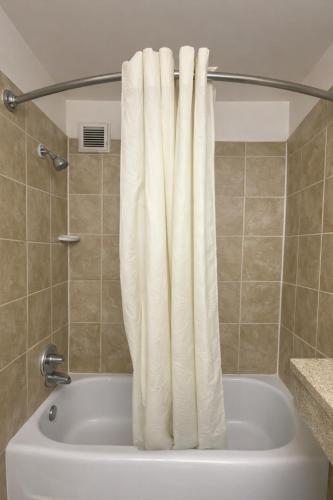 a bath tub with a white shower curtain in a bathroom at Country Host Inn in Franklin