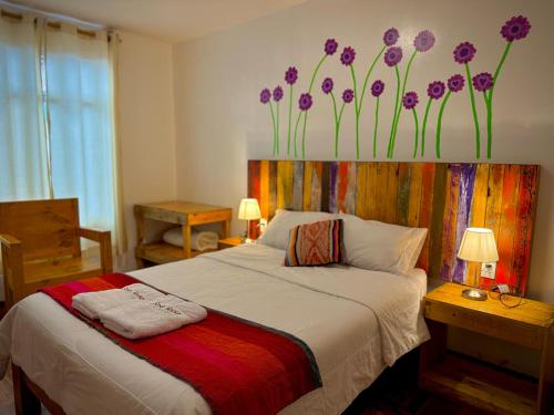 a bedroom with a bed with purple flowers on the wall at Sosa Andina House in Huaraz