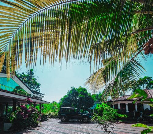 a green jeep parked under a palm tree at GB 25 cottage's in Trivandrum