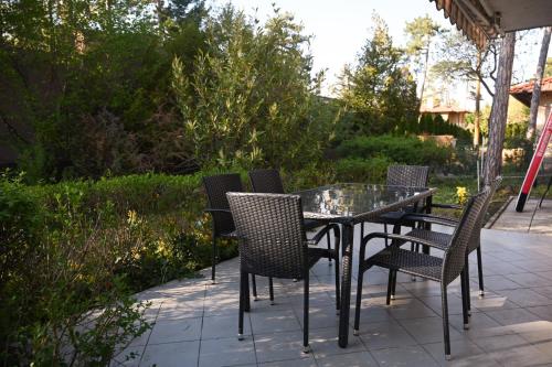 a glass table and chairs on a patio at Bogárka Apartmanház in Siófok