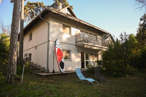 a house with a surfboard and two chairs in front of it at Bogárka Apartmanház in Siófok