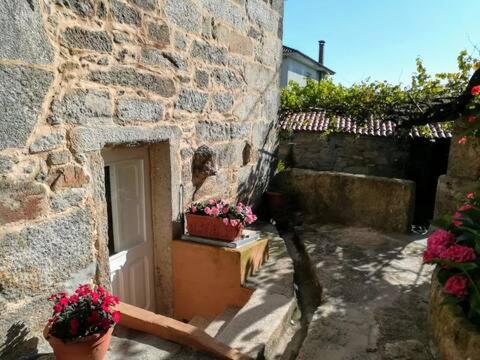 a stone building with two potted plants next to a door at La Casa del Río in Porto do Son