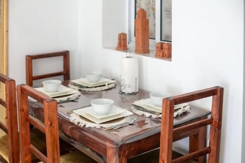 a dining room table with plates and cups and chairs at A&C Blue Haven in Chefchaouen