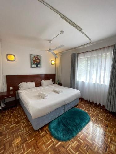 a bedroom with a large bed with a green rug at The Olive Homes in Nairobi