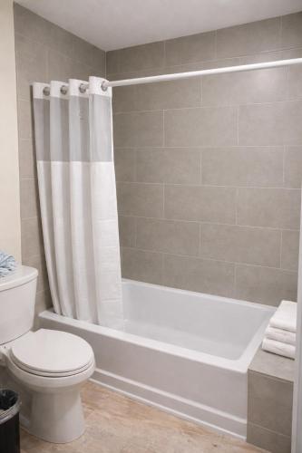 ein Badezimmer mit einer weißen Badewanne und einer Toilette in der Unterkunft The Alcala Hotel Mission Valley Seaworld in San Diego
