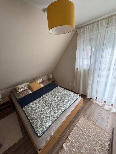 a small bed in a room with a window at JanBar Apartman in Bük
