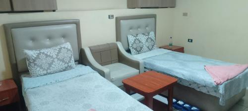 a room with two beds and a chair and a table at Mathios Hotel & Menafesha in Butajīra