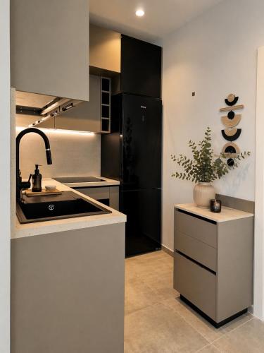 a kitchen with a sink and a black refrigerator at Green Coast Escape in Palasë