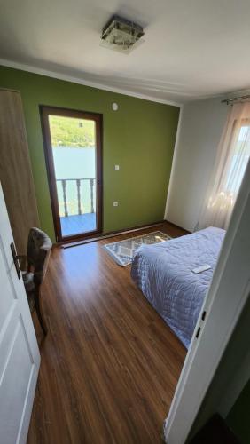 a bedroom with green walls and a bed with a window at Kuca za odmor Labud in Donji Milanovac