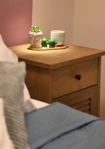 a nightstand with a table with a plant on it at Eftychia's Cozy Apartment in Sitia