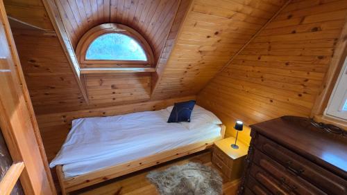 a small bedroom with a bed in a wooden cabin at Domek przy stajni in Wielki Głęboczek