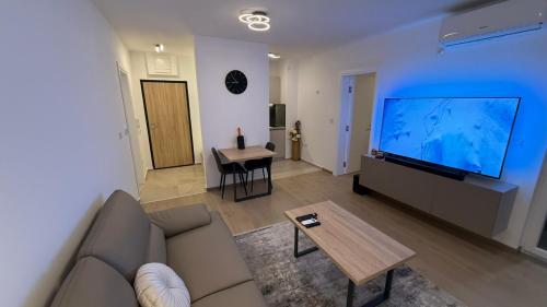 a living room with a couch and a large screen tv at Level Apartment in Kostajnica
