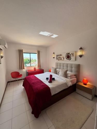 a bedroom with a large bed and a red chair at Casa Julio-Rooftop Terrace & Pool 5 Min to Beach in Carvoeiro