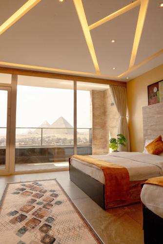 a bedroom with two beds and a large window at Petra Pyramids View in Al Kawāmil Qiblī