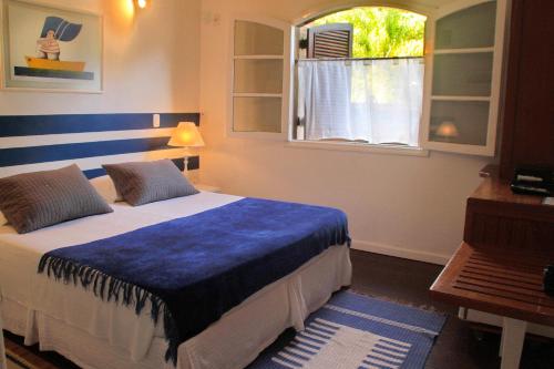 a bedroom with a bed with a blue blanket and a window at Pousada Canto do Camburi in Camburi