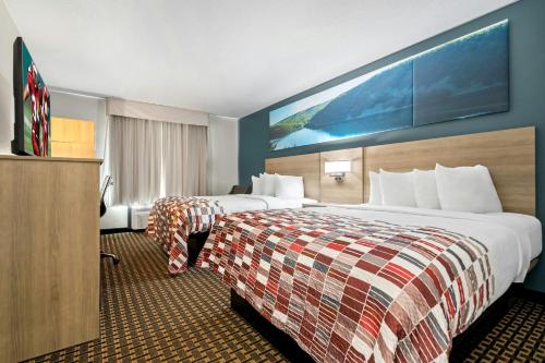 a hotel room with two beds and a large painting on the wall at Red Roof Inn & Suites Tomah in Tomah