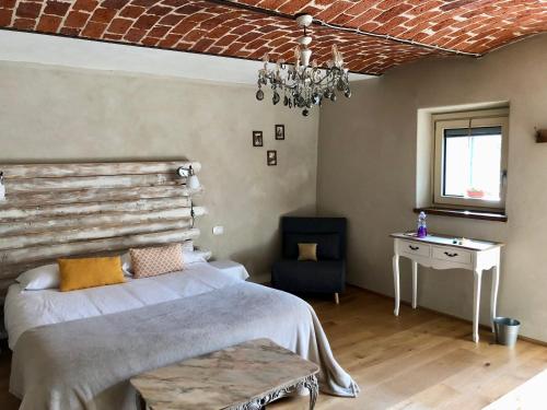 a bedroom with a bed and a table and a chandelier at La Mela Antica in Cherasco