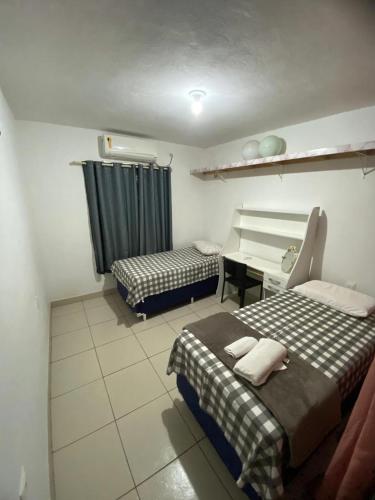a room with two beds and a desk and a table at quintal293 in Recife