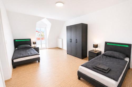 a bedroom with two beds and a black cabinet at LETA Homes - Komfortable FeWo mit Traumbalkon mit flexiblem, Self-Check-In & eigenen Parkplätzen in Straubing