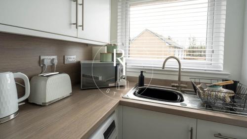 a kitchen with a sink and a microwave at The Den at Abernethy in Peterhead