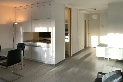 a kitchen with white cabinets and a table and chairs at Appartement im Park in Minusio