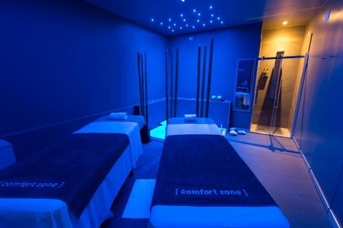 quatro camas num quarto com iluminação azul em Methis Hotel & SPA em Pádua