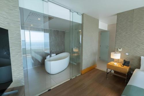 a bathroom with a tub and a glass wall at Terrado Suites Antofagasta in Antofagasta