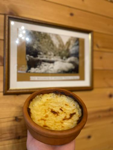 a person holding a bowl of food in front of a picture at Bujtina Shpella e Plakës Çerçan in Librazhd