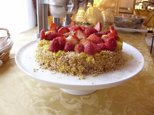 a cake with strawberries on a plate on a table at Hotel del Centro in Palermo