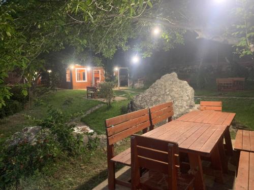 a wooden table and bench in front of a cabin at Bujtina Shpella e Plakës Çerçan in Librazhd