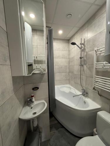 a bathroom with a tub and a sink and a toilet at Vecpilsētas apartaments in Cēsis