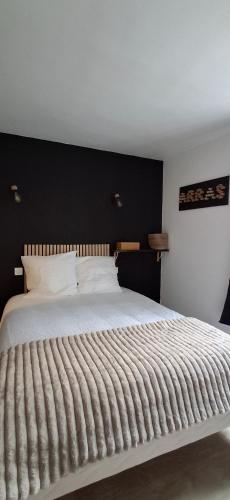 a bedroom with a large white bed with a black headboard at Le Désiré in Arras