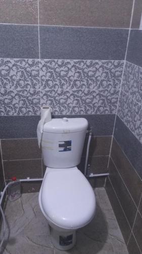 a white toilet in a bathroom with a tile wall at dar fatma matmata in Matmata