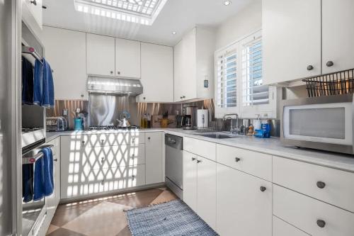 a kitchen with white cabinets and a microwave at Salty Sunrise in Aptos
