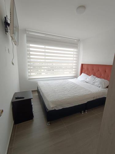 a bedroom with a bed and a window with a blind at Penthouse Barú - Usaquén in Bogotá