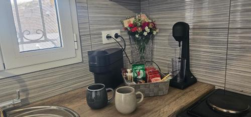 a kitchen counter with a vase of flowers and coffee cups at ΜaryAnn`s house 2 in Livadakia