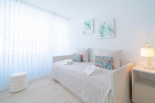 a white room with a bed and a lamp at Nina da Nazare in Nazaré