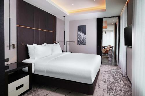 a bedroom with a large white bed and a living room at Hilton Belgrade in Belgrade