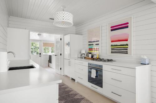 a white kitchen with white cabinets and a sink at Beach Bungalow Upper Unit Steps To Shore in Isle of Palms