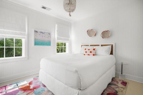 a white bedroom with a large white bed and windows at Beach Bungalow Upper Unit Steps To Shore in Isle of Palms