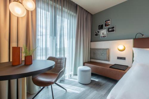 a hotel room with a bed and a desk and a table at Hilton Garden Inn Mannheim in Mannheim