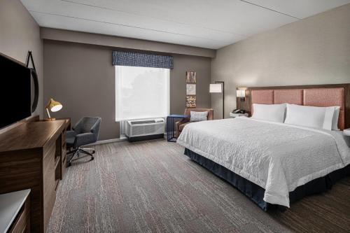a hotel room with a bed and a television at Hampton Inn Boston Woburn in Woburn