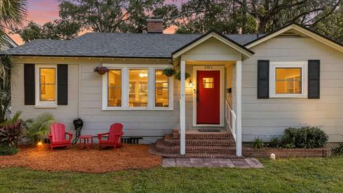 a house with two red chairs and a red door at Belote Place Bungalow in Jacksonville
